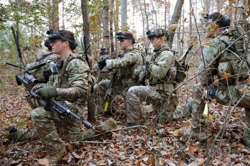 A group of soldiers kneel in the woods.