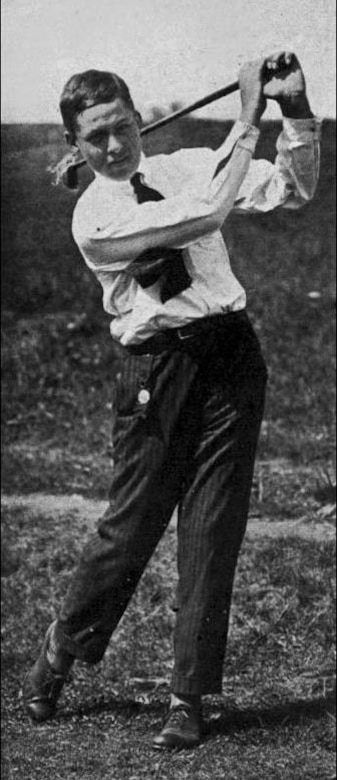 A teenage boy swings a golf club.