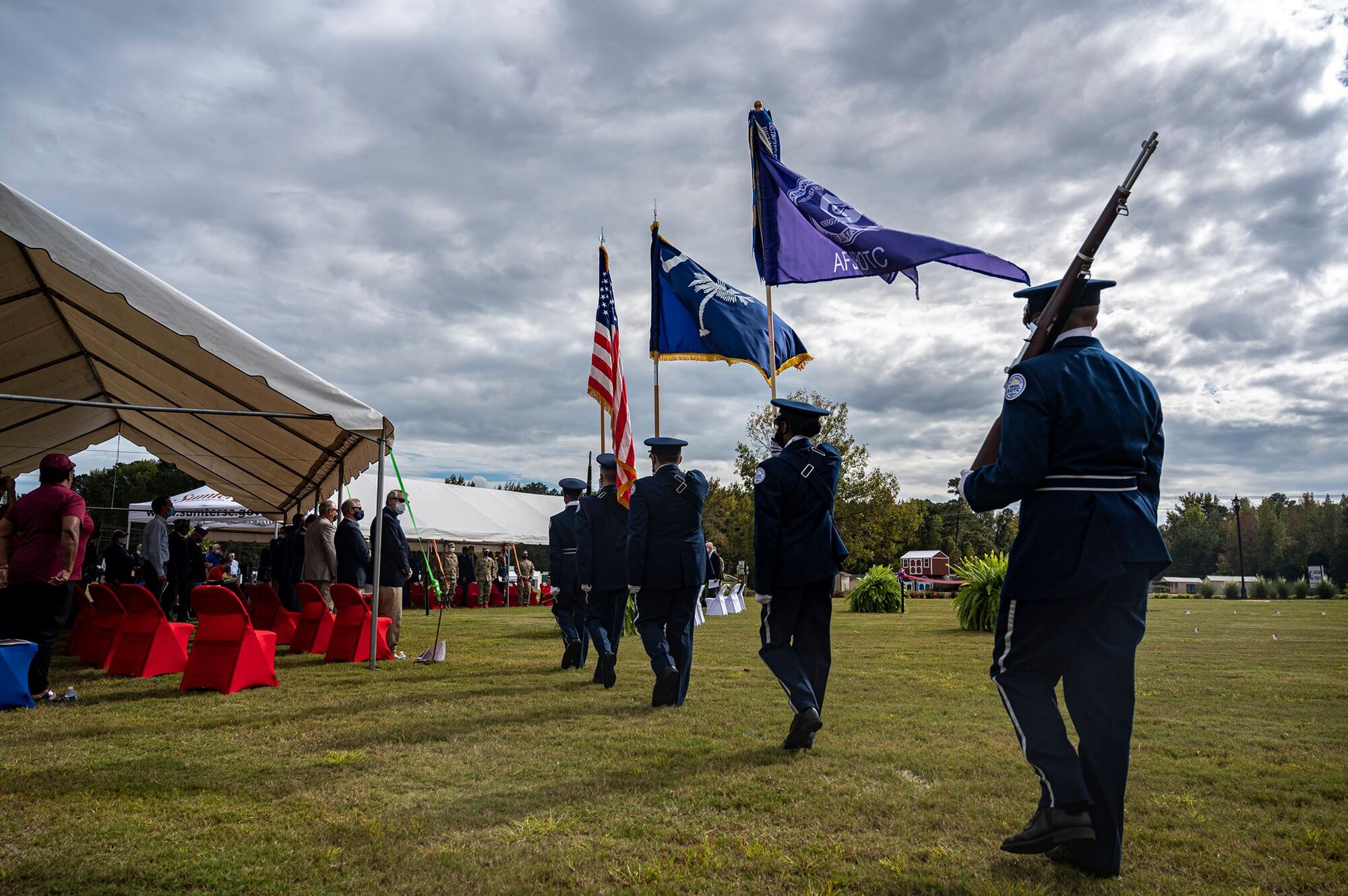 A color guard marches on a field during a ceremony.