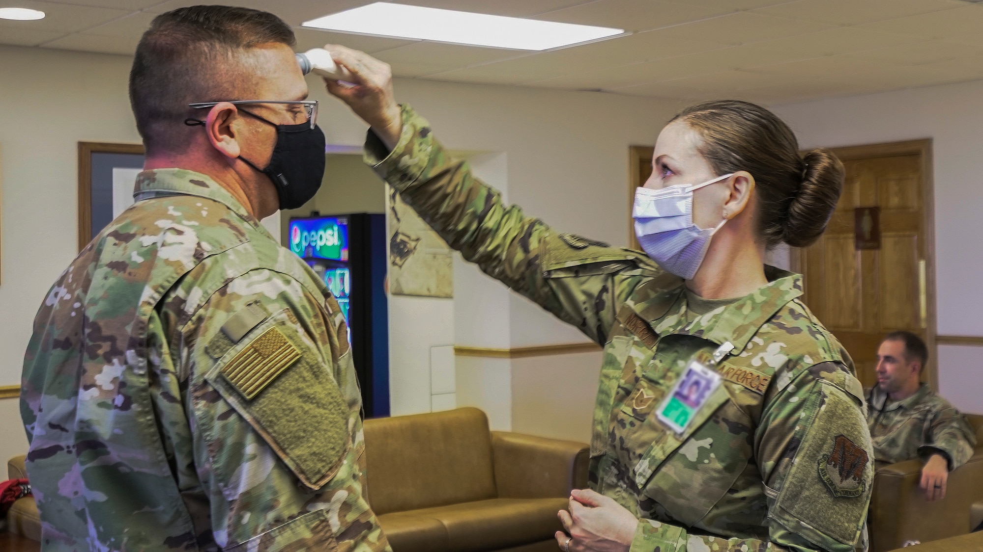 Airman gets his temperature checked by another Airman.