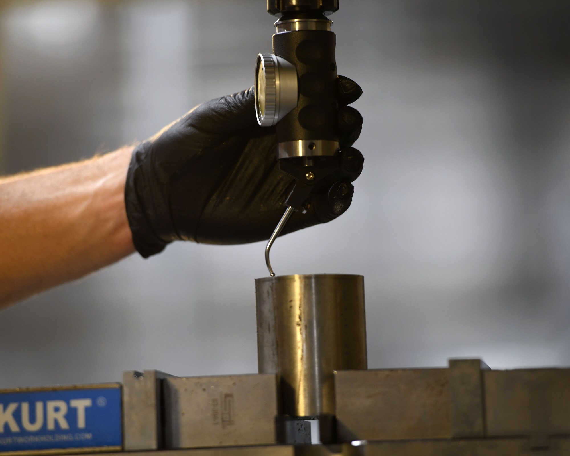 Staff Sgt. Tim Bergin guides a co-axial indicator in order to manually find the center of a part Oct. 7, 2020, at Eglin Air Force Base, Florida. The machine uses rotating multi-point tools to progressively remove material from the workpiece and produce a custom-designed part or product. (U.S. Air Force photo by Senior Airman Amber Litteral)