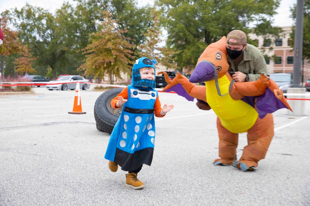 A child in a costume walks by an adult in a Halloween costume.