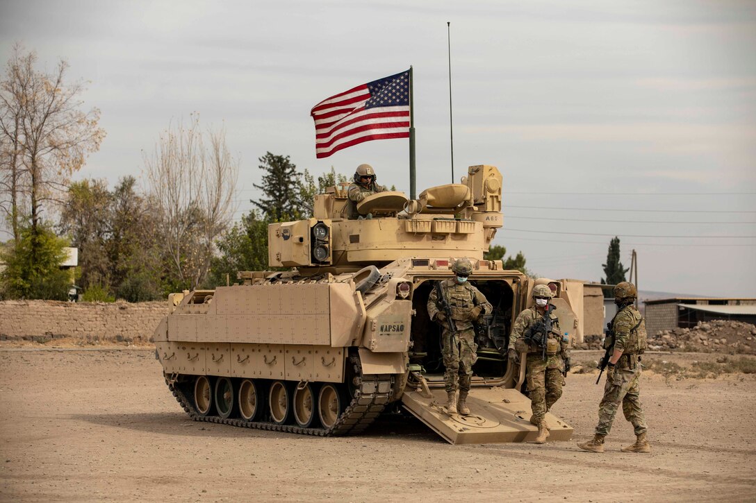 Soldiers dismount from a military vehicle.