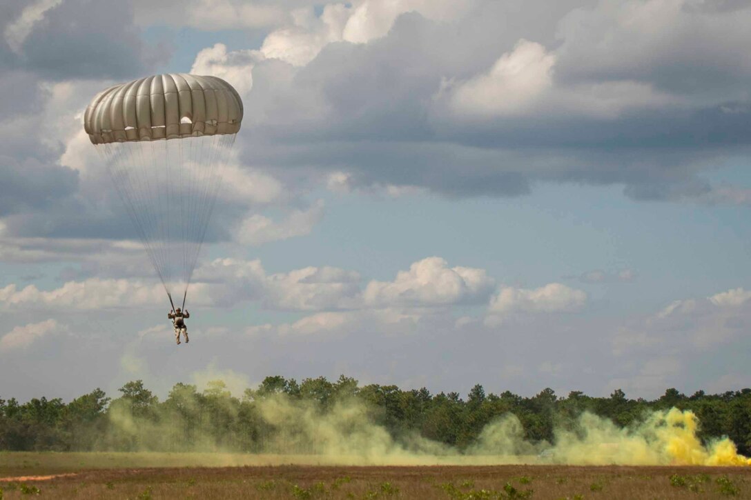 A soldier descends in the sky wearing a parachute.