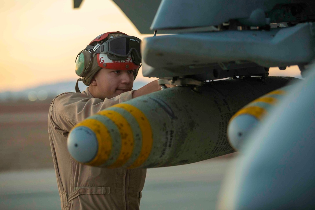 A Marine inspects an ordnance on a military aircraft.