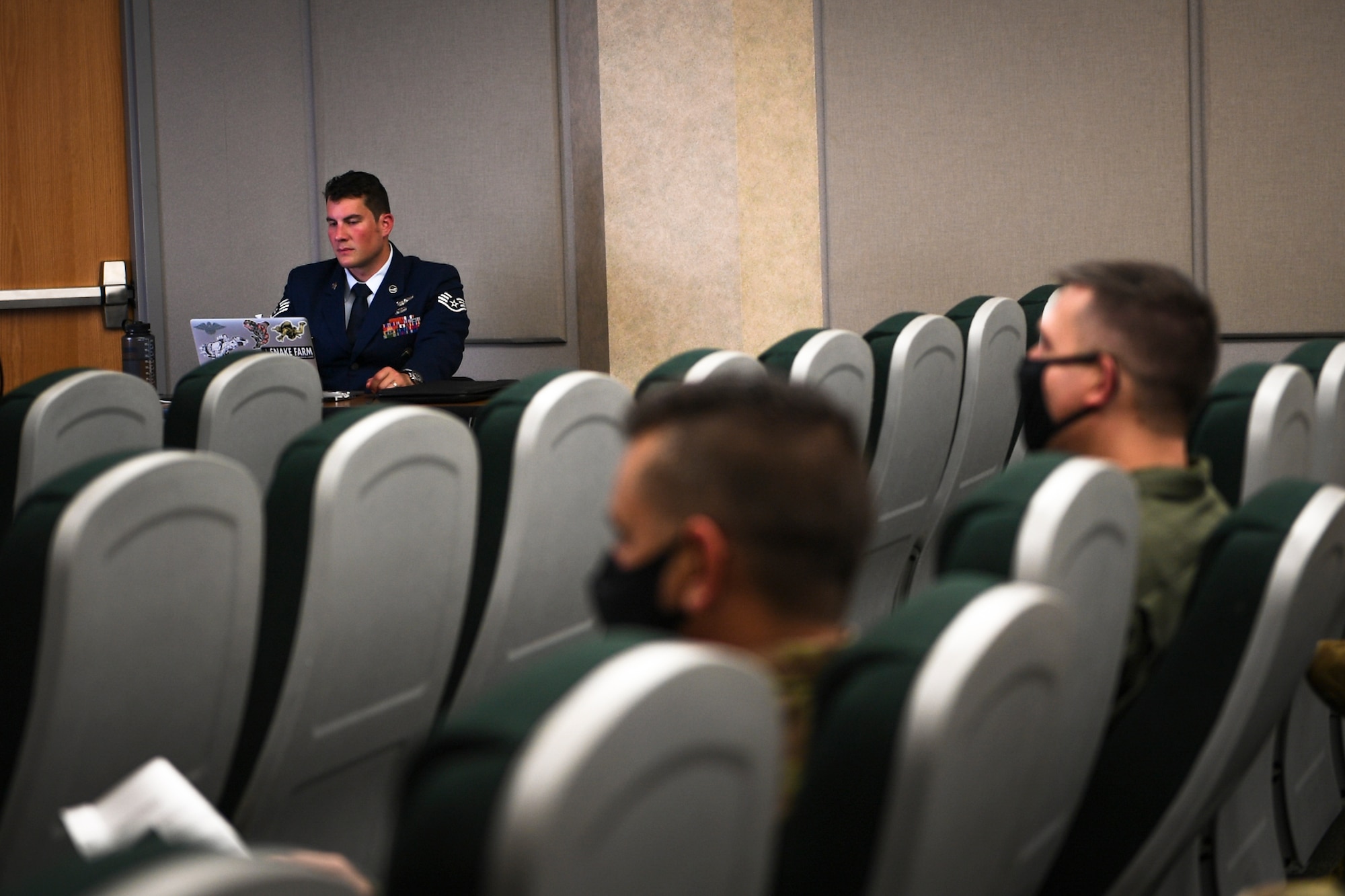 A photo of Airmen listening to a virtual ceremony