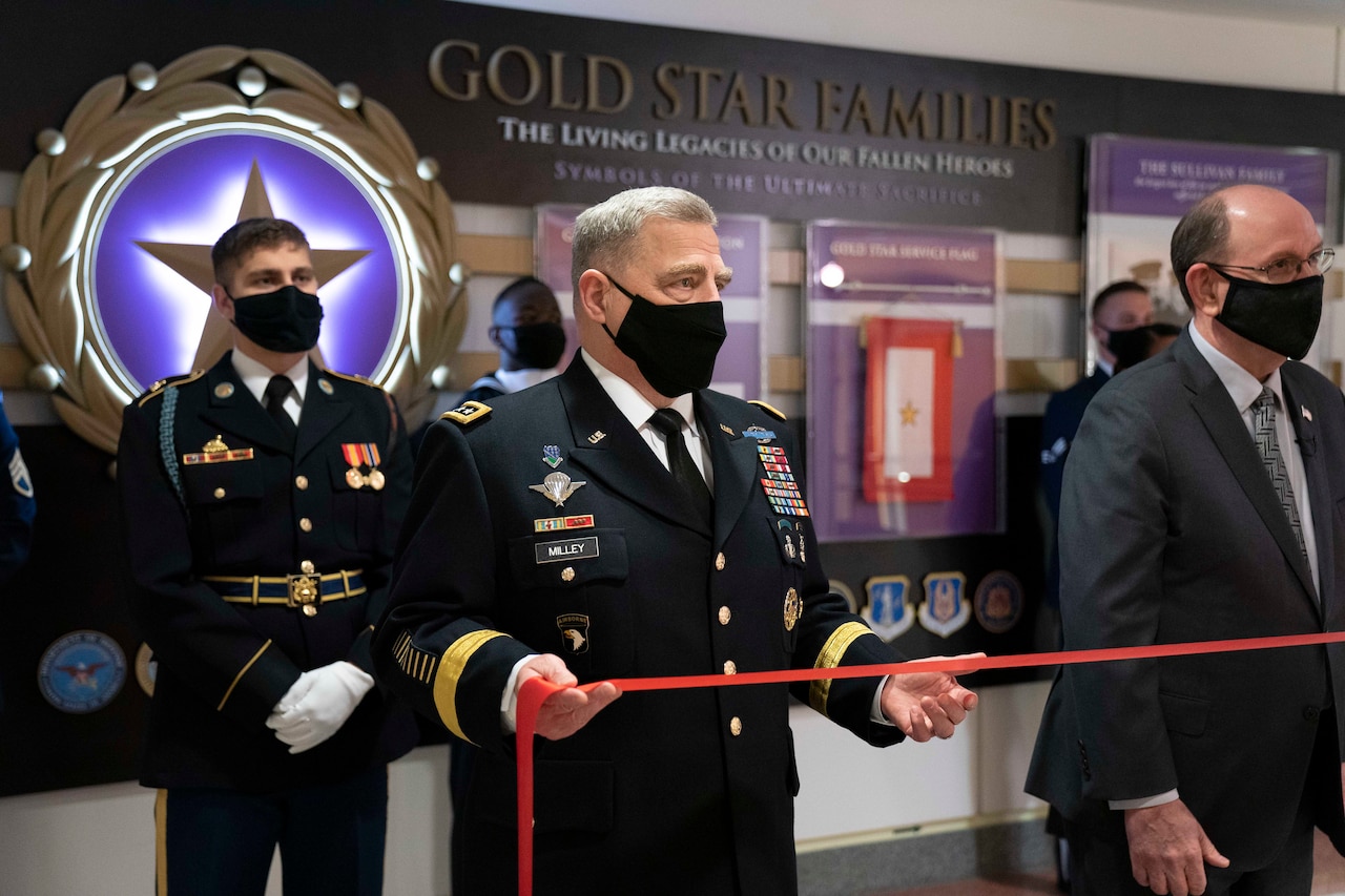 A man in a military uniform holds a red ribbon in his hands.