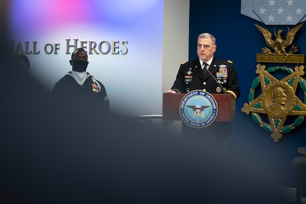 A man in a military uniform stands at a podium.