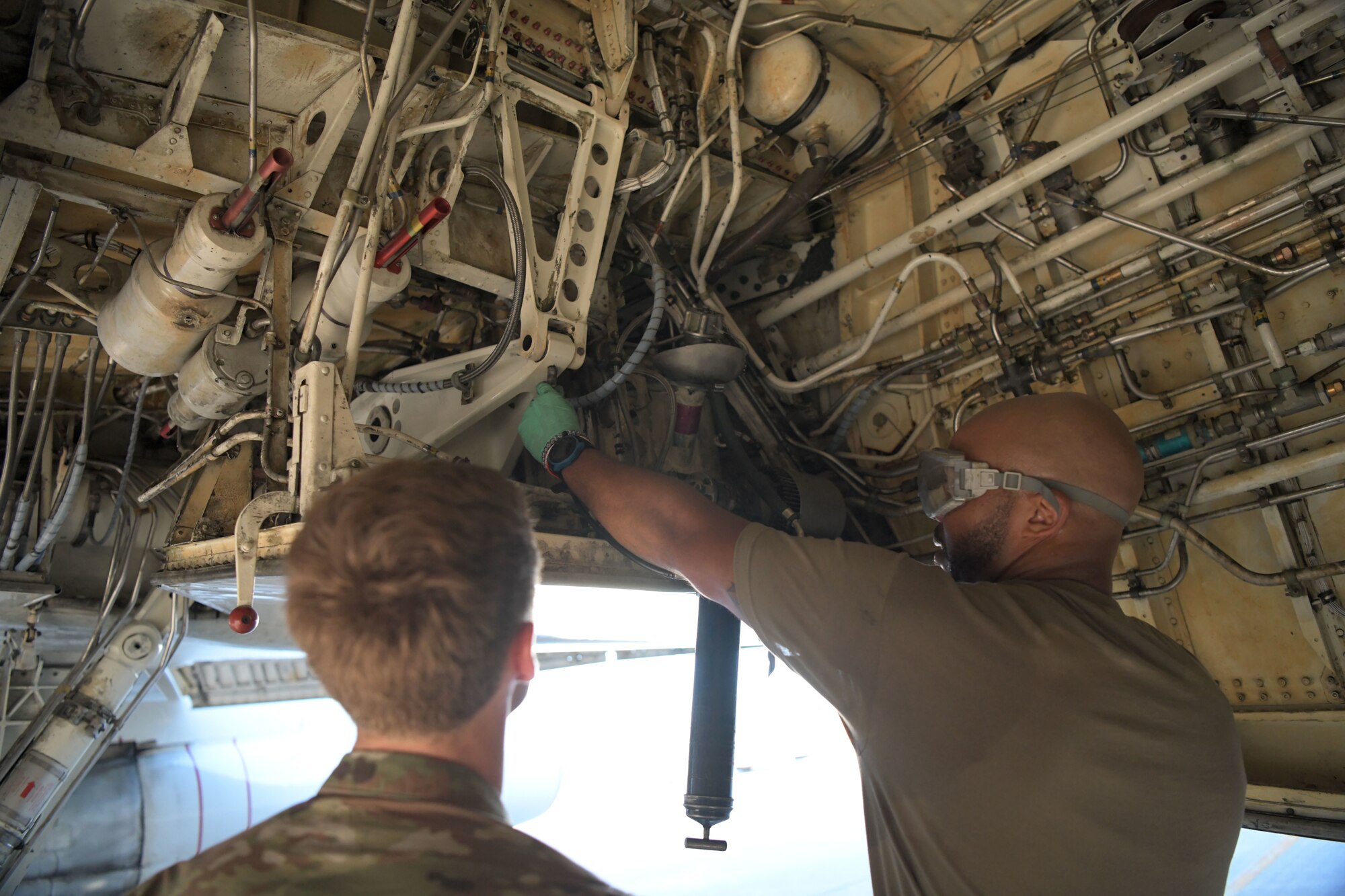 U.S. Air Force Staff Sgt. Dermayne Bullock (right), an E-8C joint surveillance target attack radar system crew chief with the 5th Expeditionary Airborne Command and Control Squadron, demonstrates proper aircraft lubrication for Airman 1st Class Zayne Day (left), a fuels systems technician also with the 5 EACCS, on Kadena Air Base, Japan, Sept. 24, 2020. The Joint STARS is an advanced ground surveillance and battle management system on the E-8C aircraft that is pertinent to supporting a free and open Indo-Pacific. (U.S. Air Force photo by Airman 1st Class Rebeckah Medeiros)