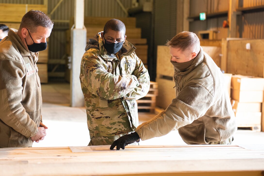 U.S. Air Force Staff Sgt. Matthew Stevens, right, 420th Munitions Squadron conventional maintenance crew chief, briefs Maj. Gen. Randall Reed, center, Third Air Force commander, and Chief Master Sgt. Randy Kwiatkowski, left, Third Air Force command chief, about the wood handling facility at Royal Air Force Welford, England, Oct. 28, 2020. The Third Air Force command team toured six bases in the 501st Combat Support Wing as part of a new commander’s immersion tour. (U.S. Air Force photo by Senior Airman Jennifer Zima)