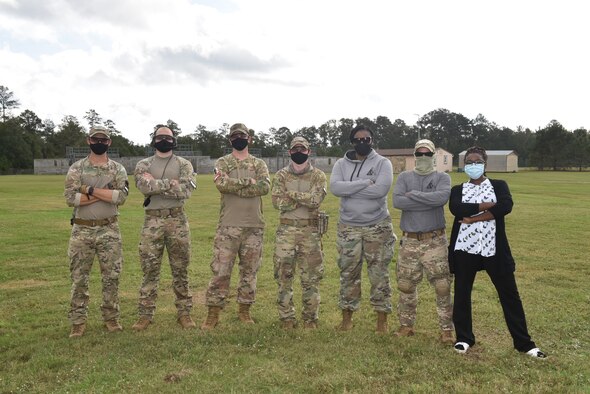 Photo shows group of people standing with arms crossed.