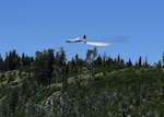 About 150 feet above a tree line, a California Air National Guard C-130 aircraft releases 3,000 gallons of water, covering nearly a quarter mile, during aerial wild land firefighting training June 15-19, 2020, at the Tahoe National Forest.