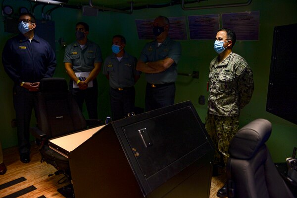 Cmdr. Richard Bentancourt, right, commanding officer of Submarine Learning Facility Norfolk (SLFN) stands in a Virginia-class Ship Control Operations Trainer (VSCOT) with Rear Adm. Thadeu Lobo, commander, Brazilian Submarine Force, and key leadership from the Brazilian delegation at the SLFN headquarters in Norfolk, Va., Oct. 27, 2020.