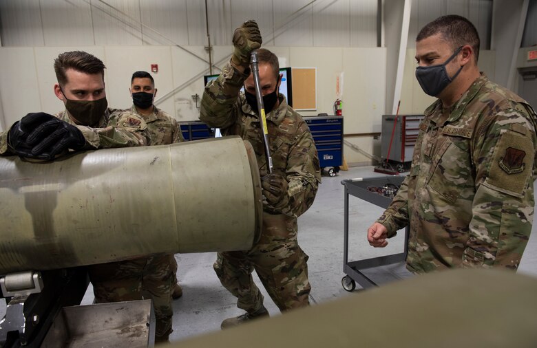 Col. Teel assists the Airmen in building a GBU by further securing the fuse that is installed into a BLU-109 bomb body.