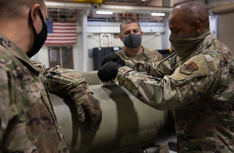 A Airman ties a fuse cable to a BLU-109 bomb body.
