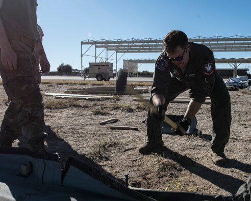 A photo of an Airman setting up a tent.