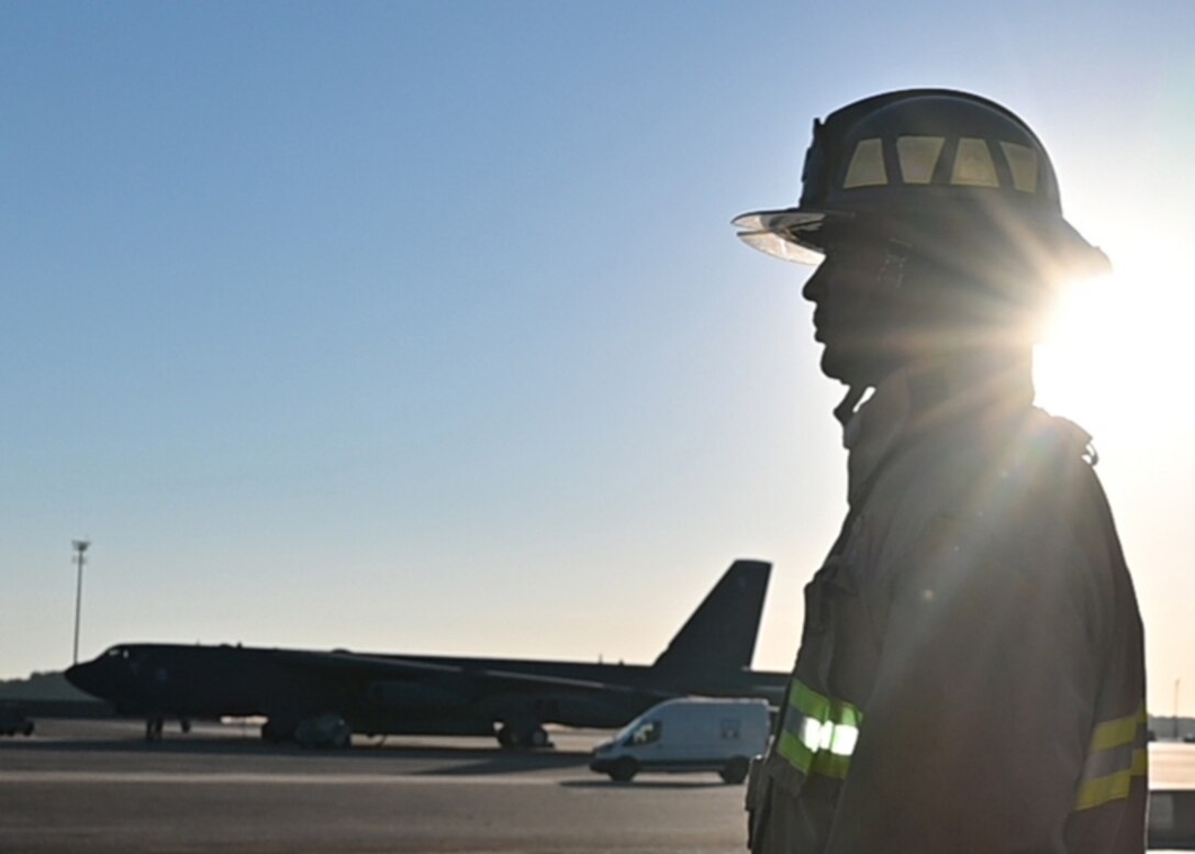A fireman is silhouetted against the morning sun.