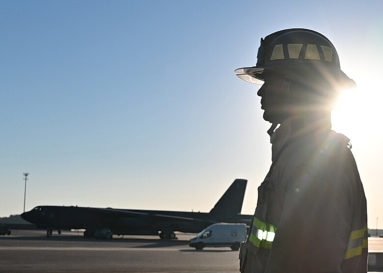 A fireman is silhouetted against the morning sun.