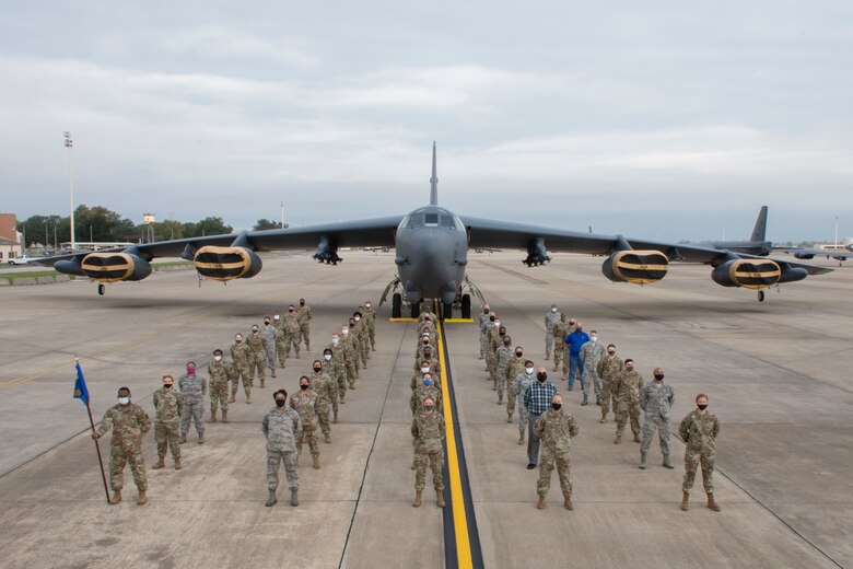 Airmen stand in formation in front of a B-52.