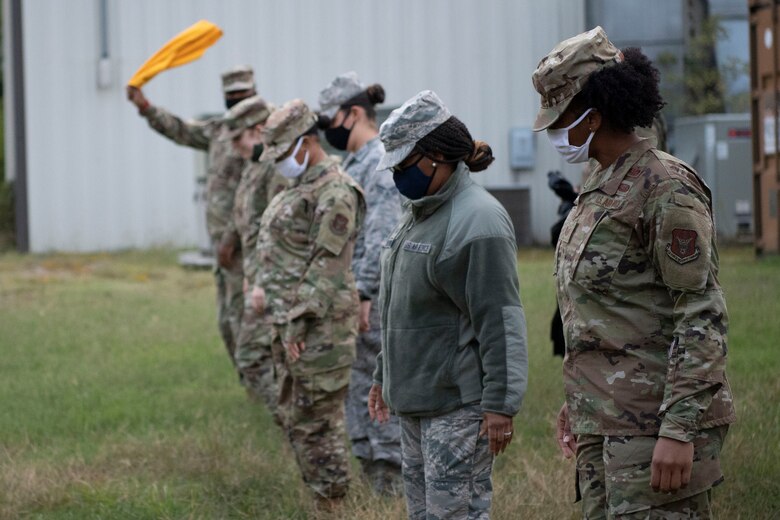 Airmen stand in a line looking for items during a mishap training exercise.