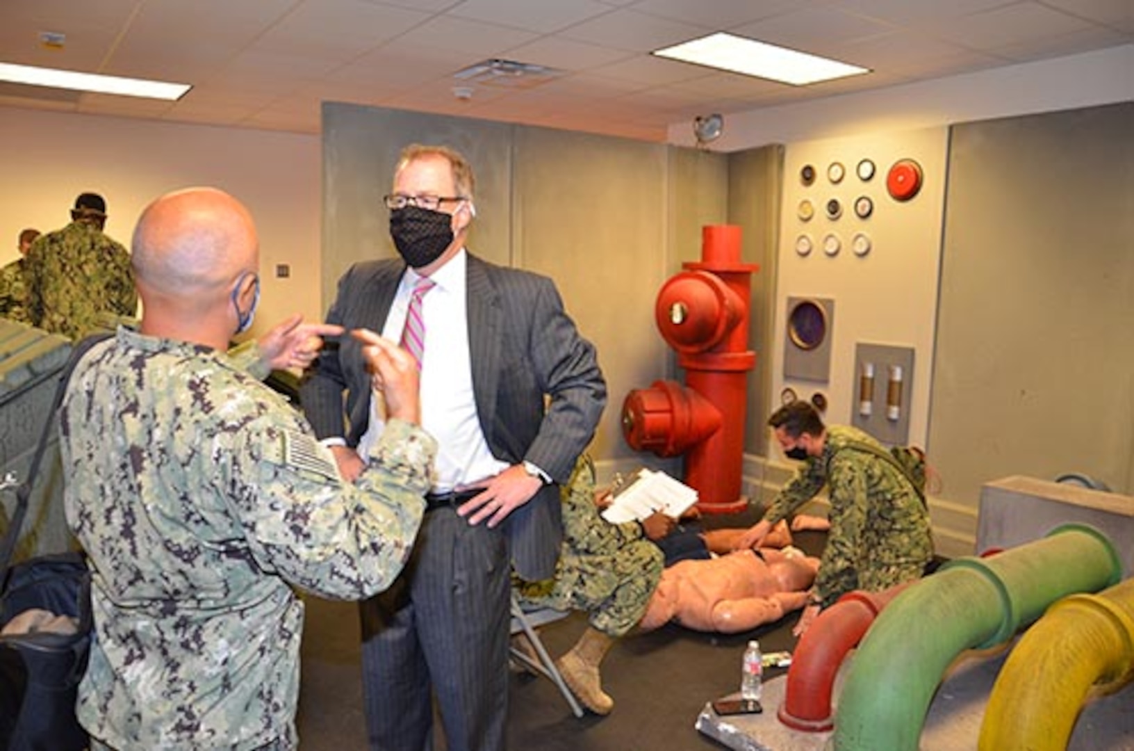 The Honorable Thomas McCaffery, Assistant Secretary of Defense for Health Affairs, is given a tour of the Shipboard Mass Casualty simulator by Cmdr. Ruben Lopez, Department Chair of the Navy Hospital Corpsman Basic program