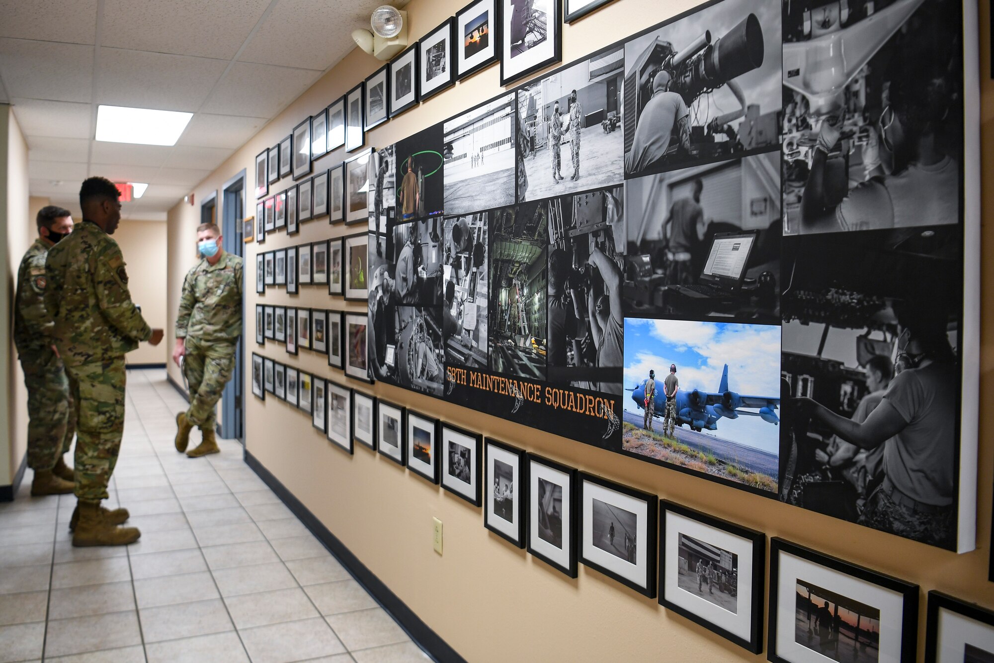 Airmen look at a wall of photos