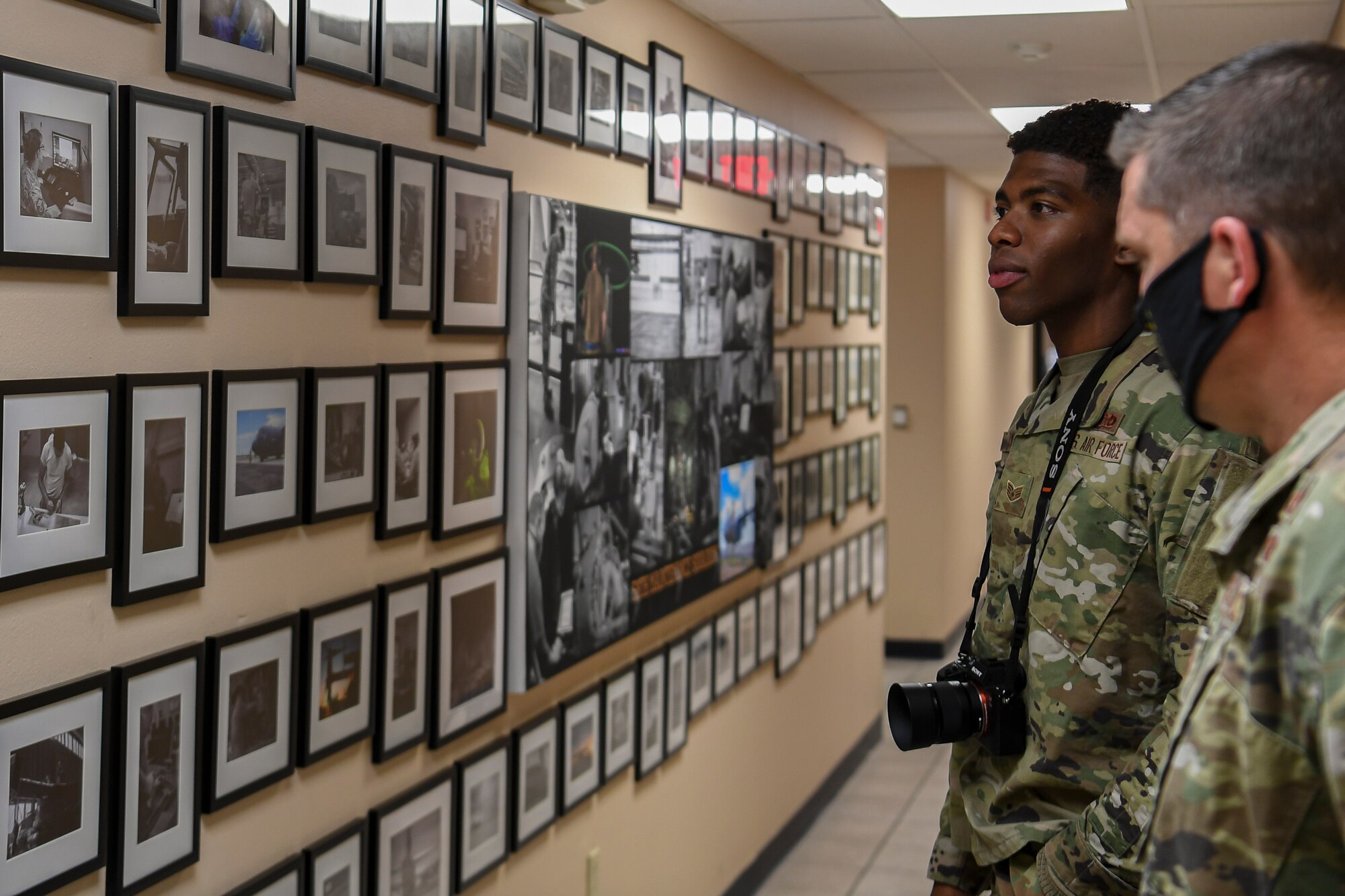 Airmen look at a wall of photographs