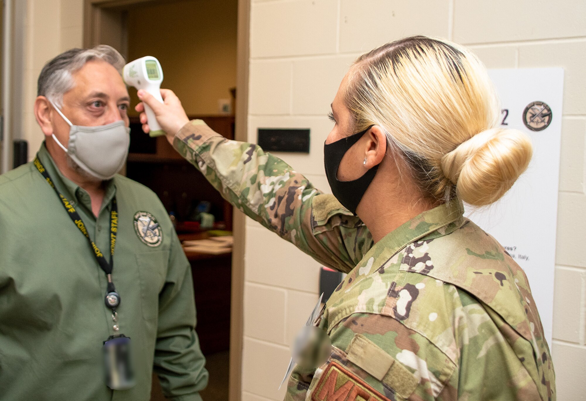 CAMP ATTERBURY, IND. (OCT. 10, 2020) Joseph Chacon, Joint Staff Bold Quest Operations Director, has his temperature checked by Technical Sergeant Alexandria Harville, an aerospace medical technician assigned to the Virginia Air National Guard 192nd Medical Group  during capability demonstration Bold Quest 20.2. Members of the 192nd Medical Group helped develop the medical standard operating procedures for Bold Quest participants to prevent and respond to any COVID-19 outbreak. (U.S. Navy photo by Mass Communication Specialist 2nd Class Jonathan Word)