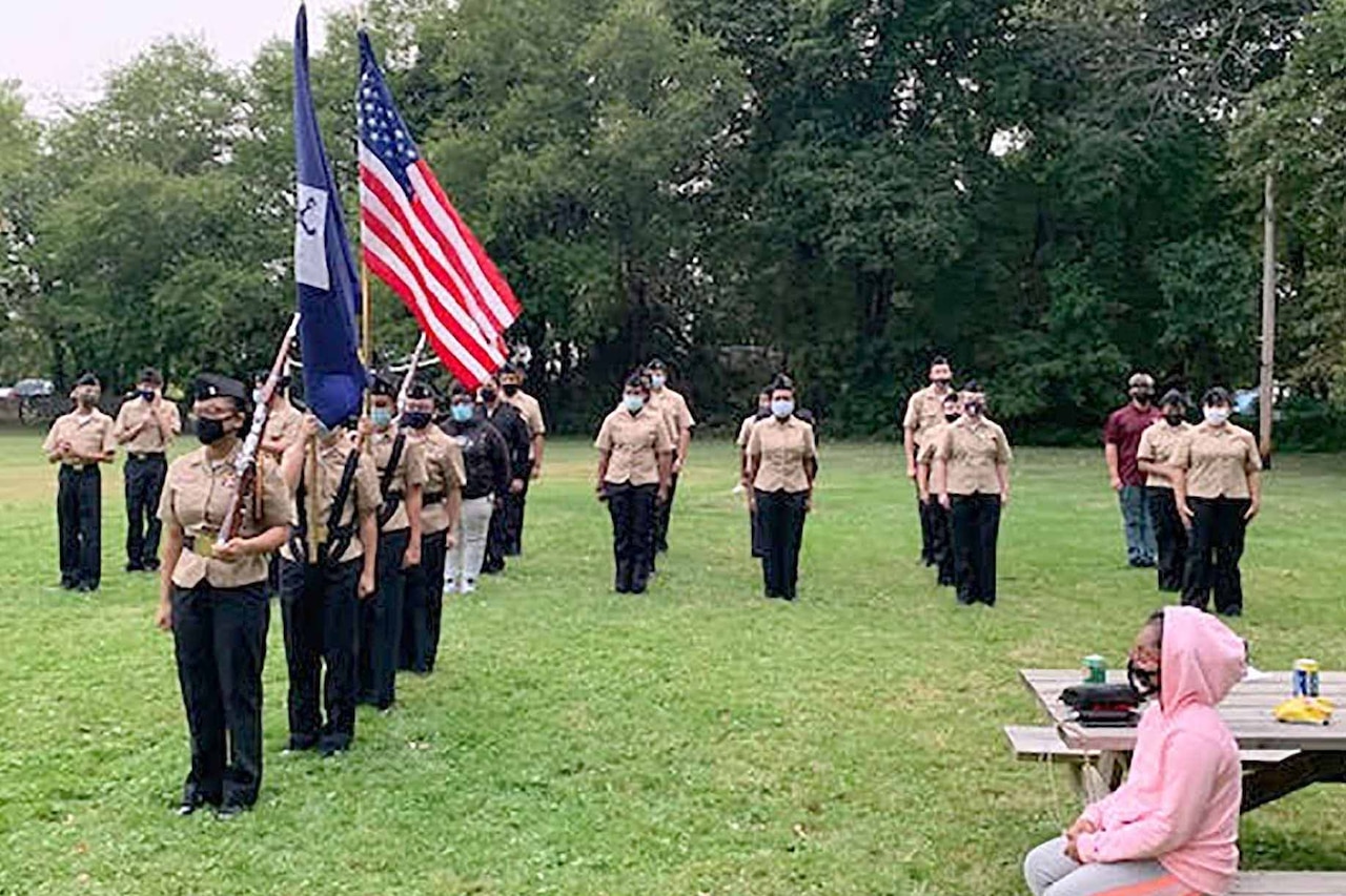 High school military cadets wearing masks conduct drills outside of their school.