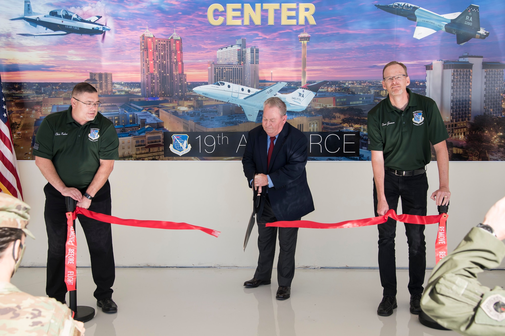 Brian Bastow, Nineteenth Air Force logistics requirements branch chief, cuts a ribbon held by Chris Padeni, Nineteenth Air Force maintenance training superintendent (right), and Dean Jeavons, Nineteenth Air Force maintenance requirements section chief (left), during the Nineteenth Air Force Maintenance Training Center activation ceremony Oct. 29, 2020, at Joint Base San Antonio-Randolph, Texas.