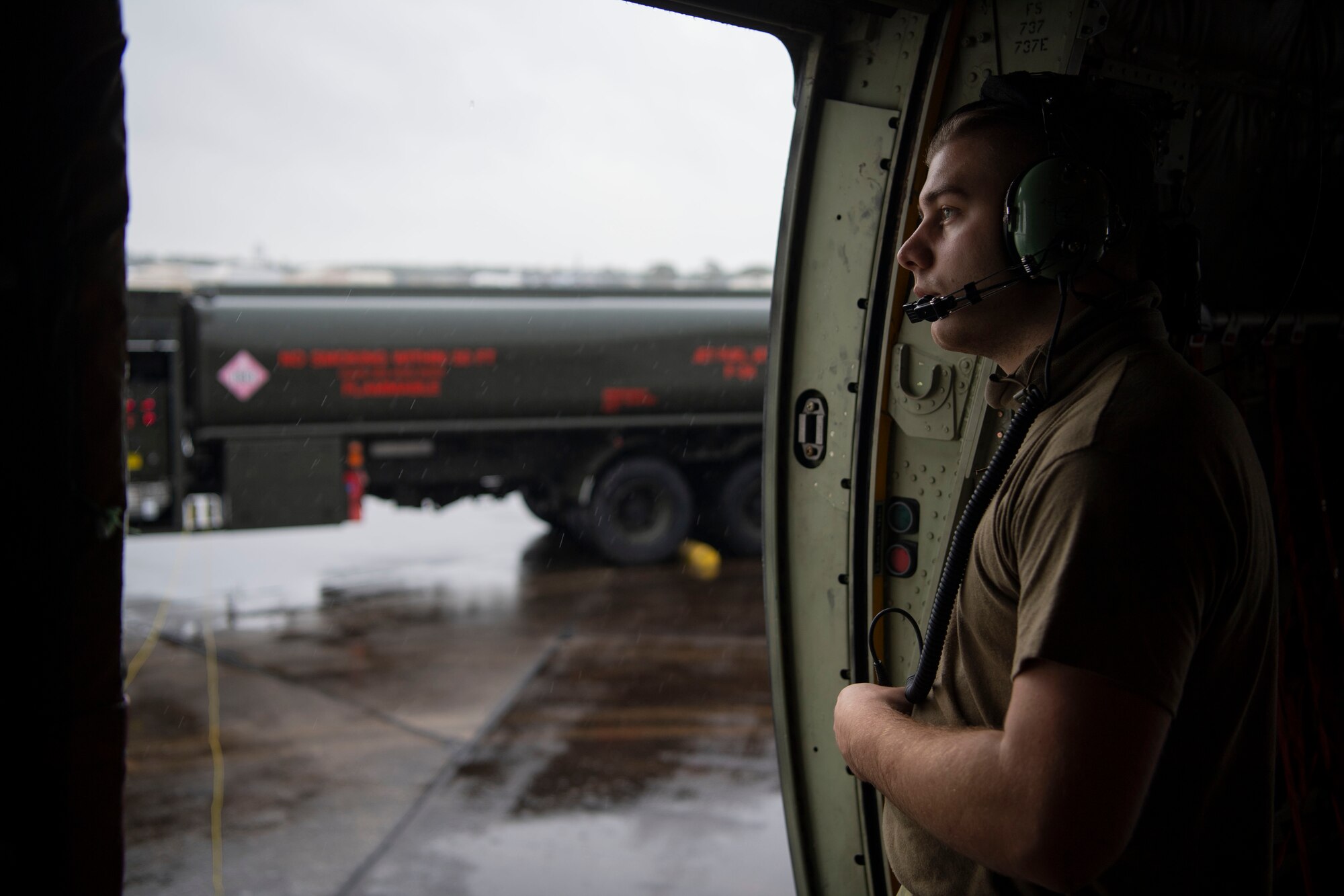 An Airman looks out the side of a C-130J.