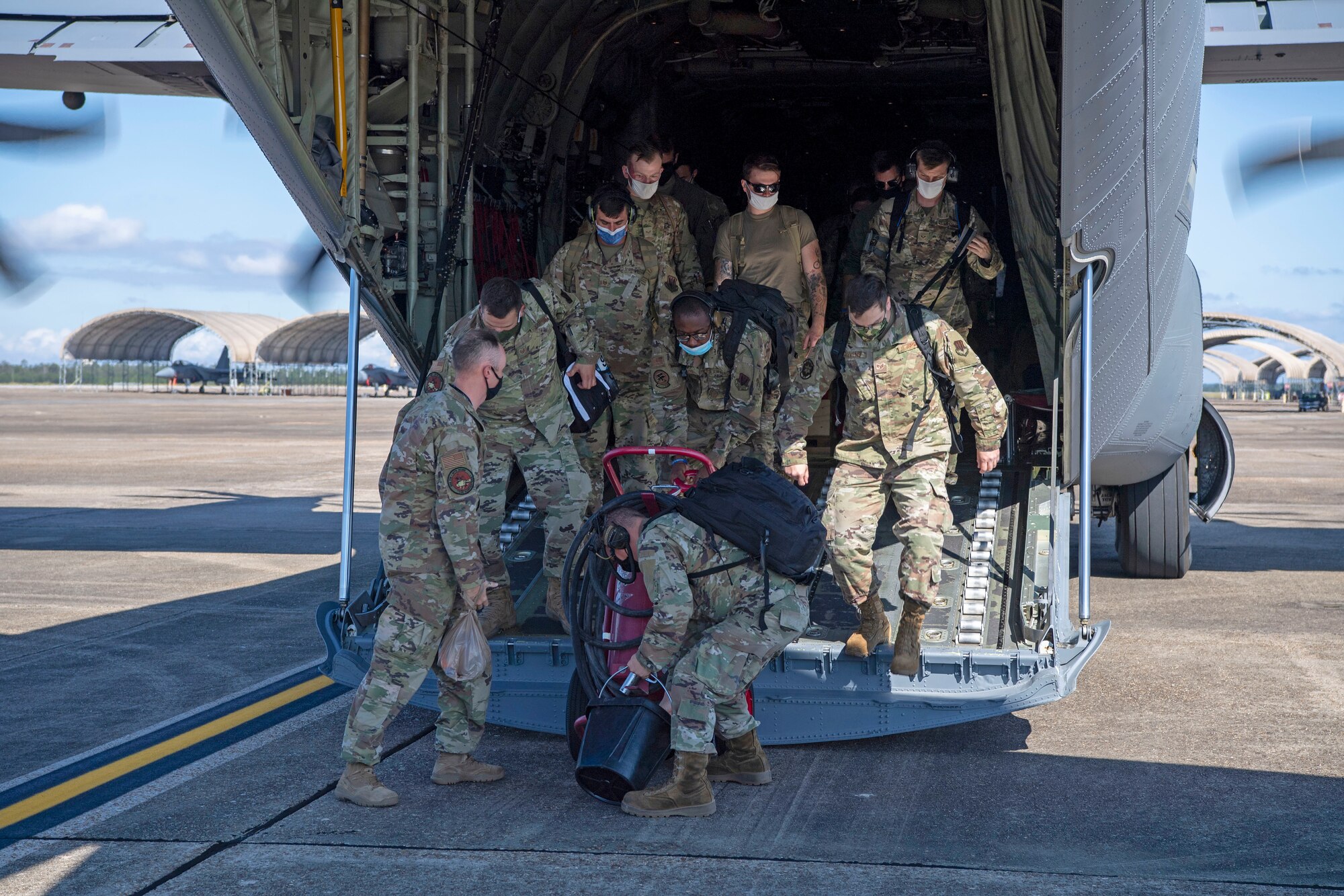 Airmen unload a fire bottle out the back of a C-130J Super Hercules.