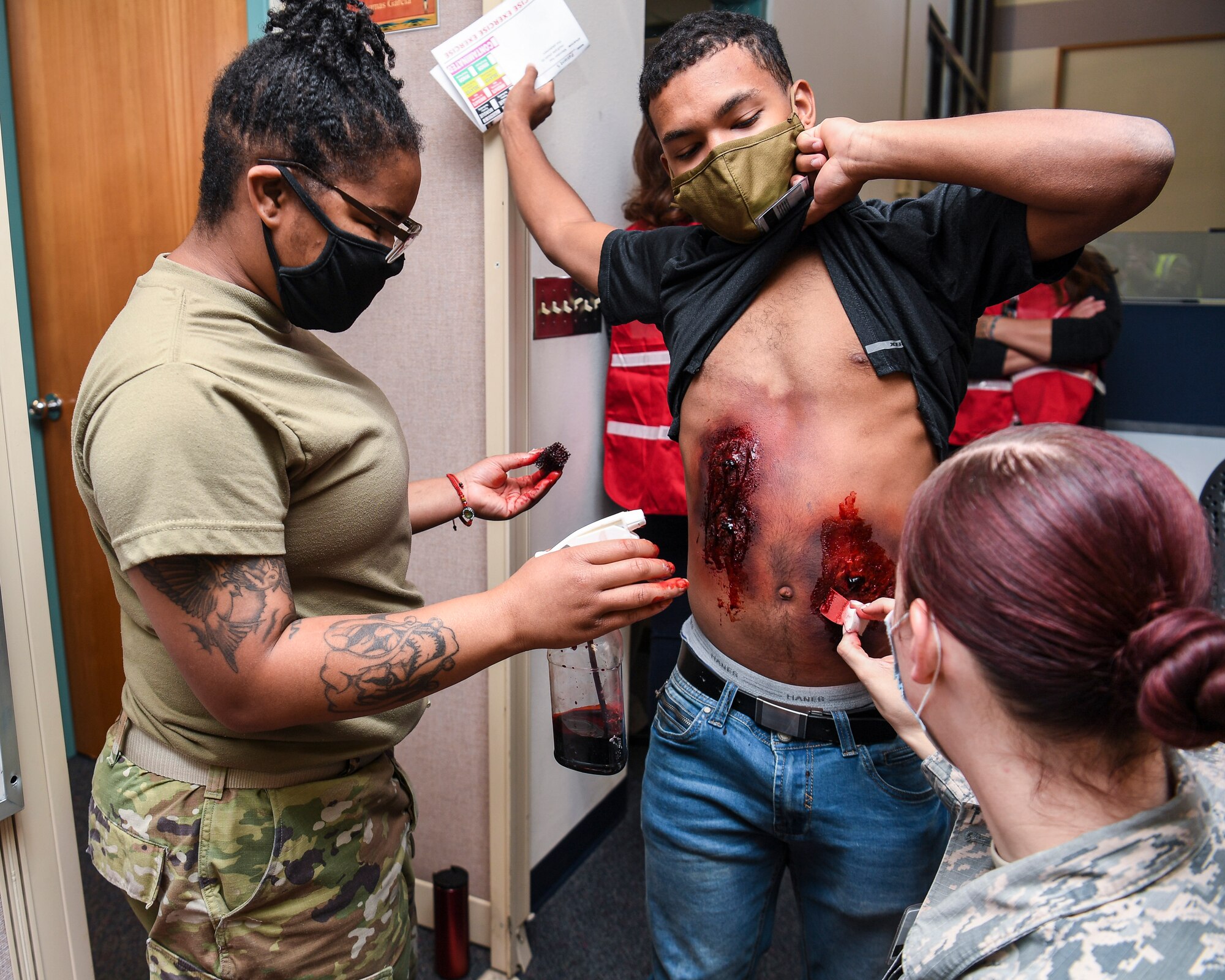 Technicians apply moulage to a simulated casualty.