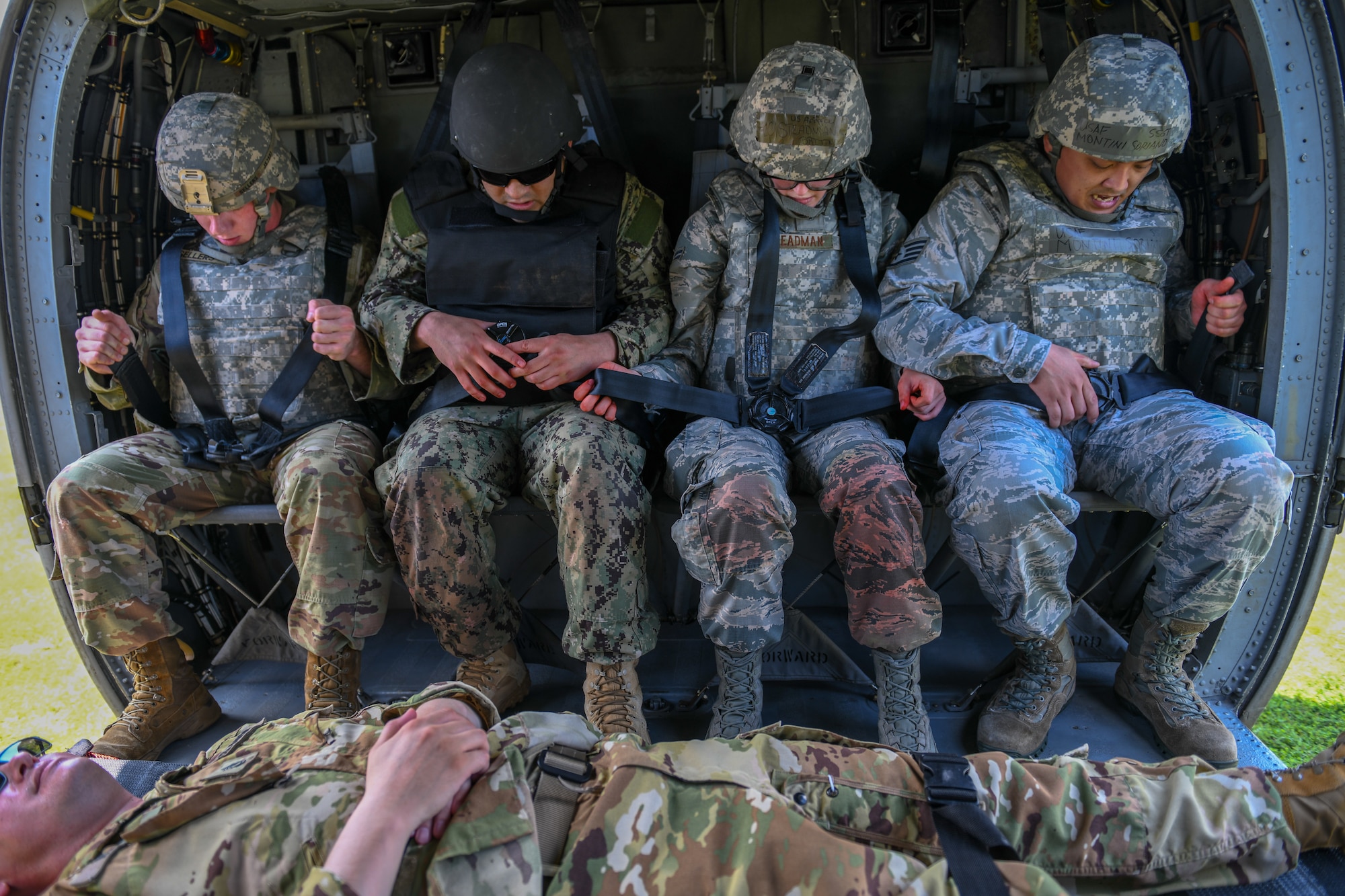 Tactical Combat Casualty Care participants buckle seat belts of UH-60 helicopter.