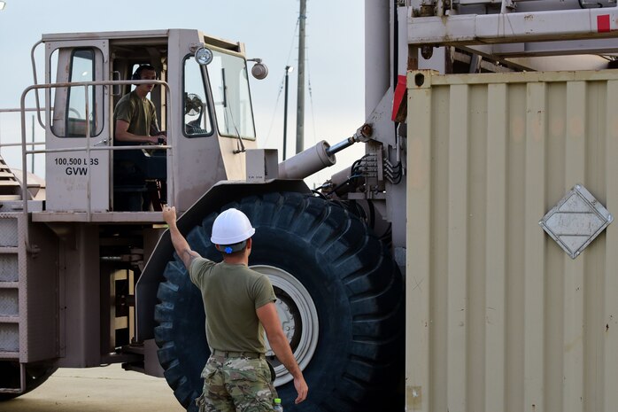 Airman 1st Class Aaron Klawitter, 8th Maintenance Squadron management stockpile technician, signals Staff Sgt. Brett Mohney, 8th MXS ammo flight munitions storage and handling technician, at Kunsan Air Base, Republic of Korea, Aug. 28, 2020. The 8th MXS loaded 45 International Organization for Standardization containers, or ISOs, filled with 6,000 pounds of munitions onto Traffic Management Office trucks. The ISO shipping containers with the munitions stored inside weigh roughly 20,000 to 35,000 pounds each. (U.S. Air Force photo by Senior Airman Jessica Blair)