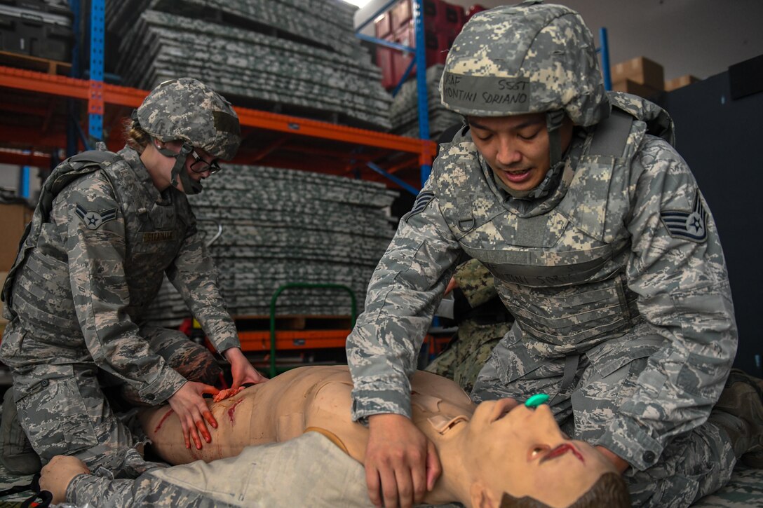 Medics interact with a wounded training mannequin during the Tactical Field Care phase of the Tactical Combat Casualty Care.