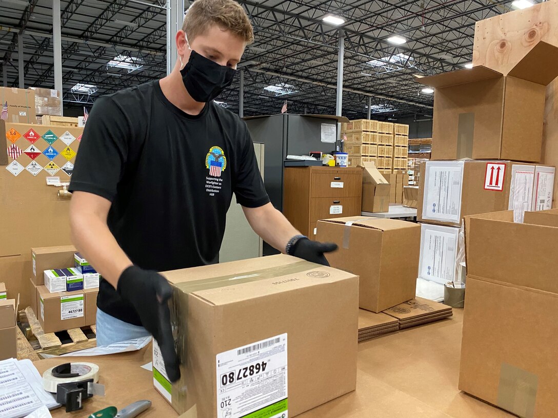 DLA Distribution employee holding onto a cardboard box