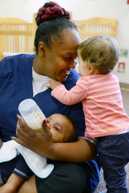 Photo of woman feeding baby and smiling at another child