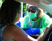 A physician’s assistant with the Michigan Air National Guard gives an Ottawa County resident a COVID-19 test in Holland, Mich., Aug. 16, 2020.
