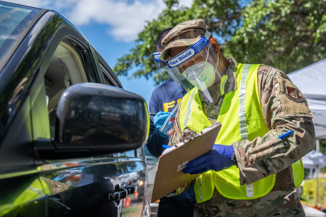 A service member holds a clipboard as he speaks to a motorist.