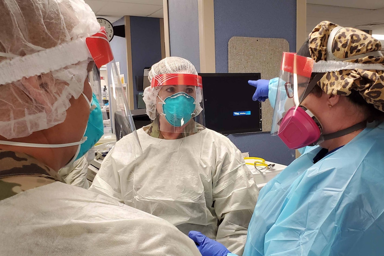 People wearing personal protective equipment in a hospital are having a discussion.