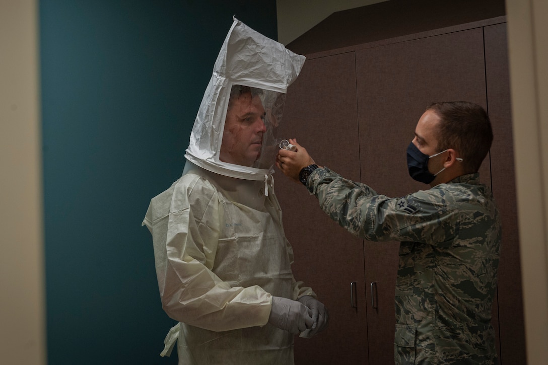 Photo of an Airman spraying solution for a mask fitting