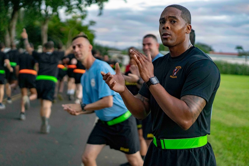 Soldiers in running clothes on the sidelines encourage runners.