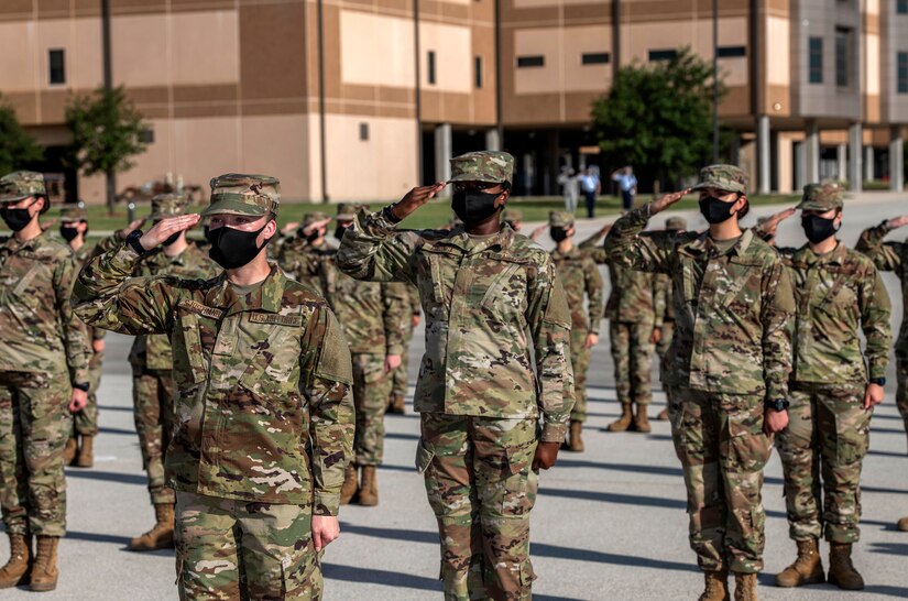 Air Force recruits in uniform and in formation salute.