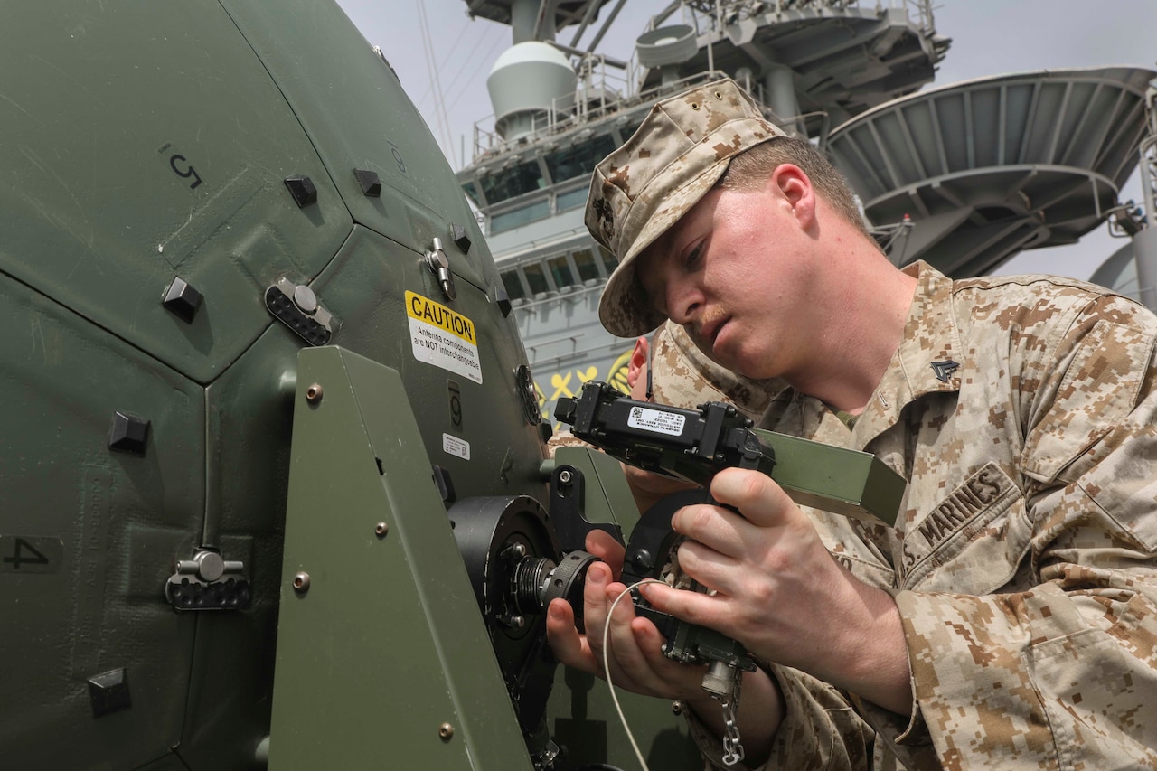 A Marine examines a satellite component