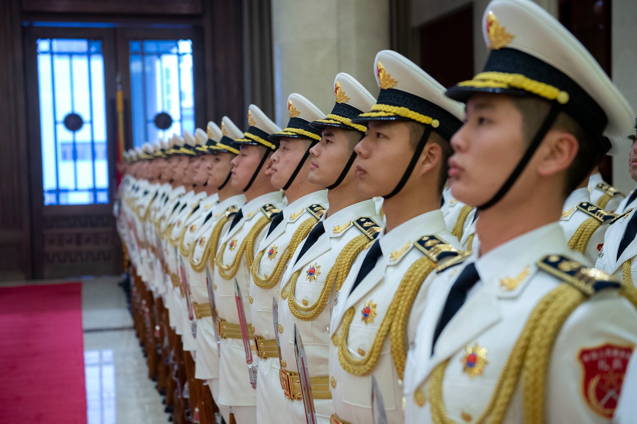 Young men in military uniforms stand shoulder-to-shoulder.