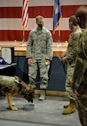 Military Working Dog Tedy's handler speaks with the wing command chief as Tedy enjoys a steak following his retirement ceremony.