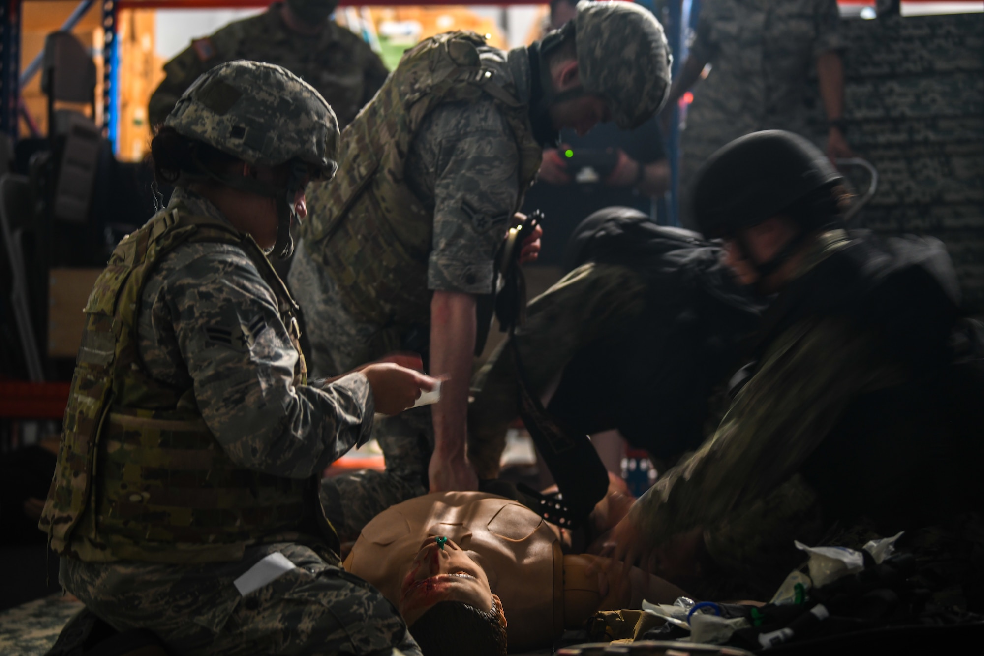 Air Force and Navy medical personnel interact with a wounded training mannequin.