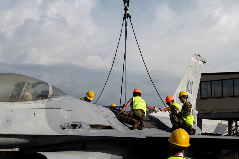 Airmen from the 31st Maintenance Squadron and 52nd MXS attach a lifting sling to an F-16 Fighting Falcon at Aviano Air Base, Italy, Aug. 29, 2020. The sling was attached to a crane and used to lift the aircraft during a training event. (U.S. Air Force photo by Senior Airman Caleb House)