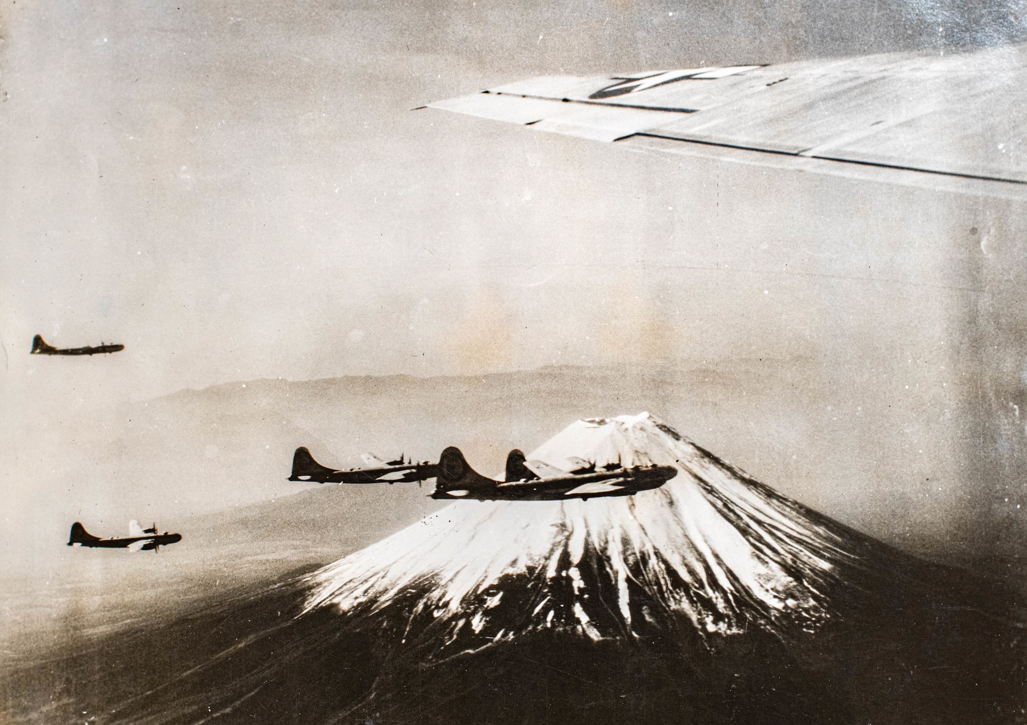 Several B-29 Superfortresses fly near Mount Fuji in Japan during World War II.